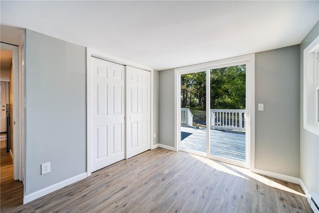 unfurnished bedroom with access to exterior, a closet, and light wood-type flooring