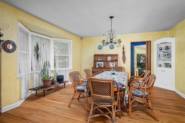 dining space featuring hardwood / wood-style flooring, built in features, and a chandelier