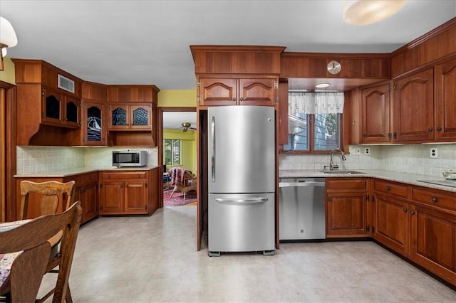 kitchen featuring decorative backsplash, sink, stainless steel appliances, and light stone counters