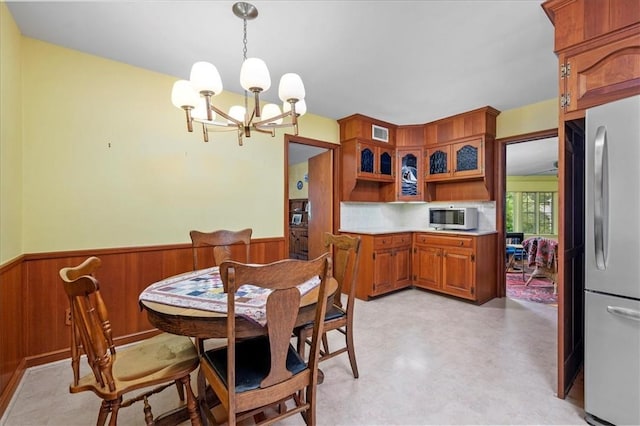 dining area with an inviting chandelier and wooden walls