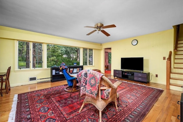 living room featuring ceiling fan, a healthy amount of sunlight, light wood-type flooring, and a baseboard radiator