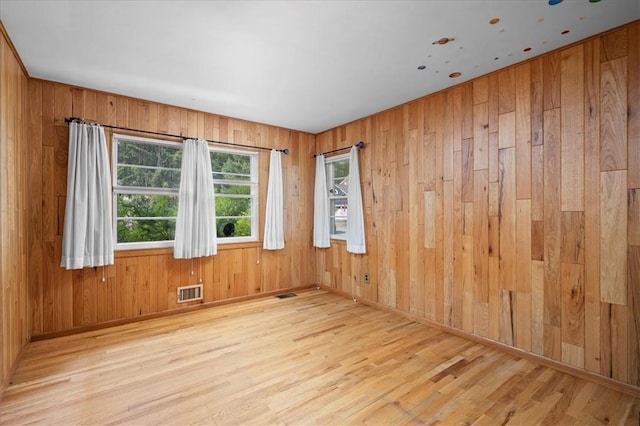 unfurnished room featuring wood walls and light wood-type flooring