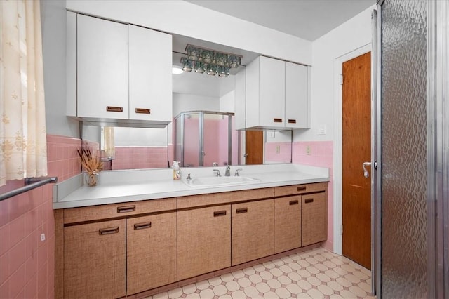 bathroom featuring vanity, a shower with door, and tile walls