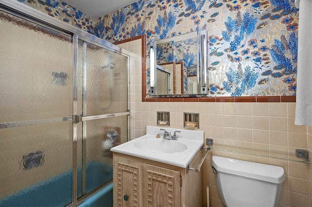 full bathroom with shower / bath combination with glass door, vanity, tile walls, and toilet