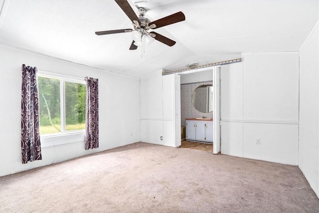 unfurnished bedroom featuring ceiling fan, lofted ceiling, ensuite bathroom, and light carpet