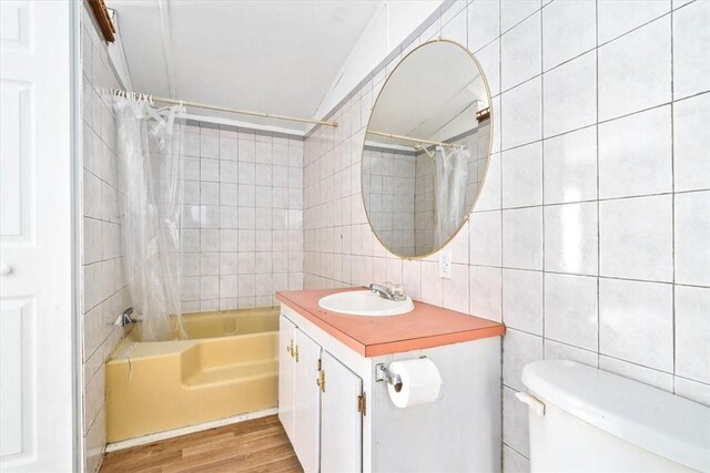 full bathroom featuring vanity, toilet, tile walls, wood-type flooring, and shower / tub combo