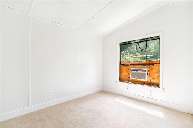 carpeted spare room featuring cooling unit and vaulted ceiling