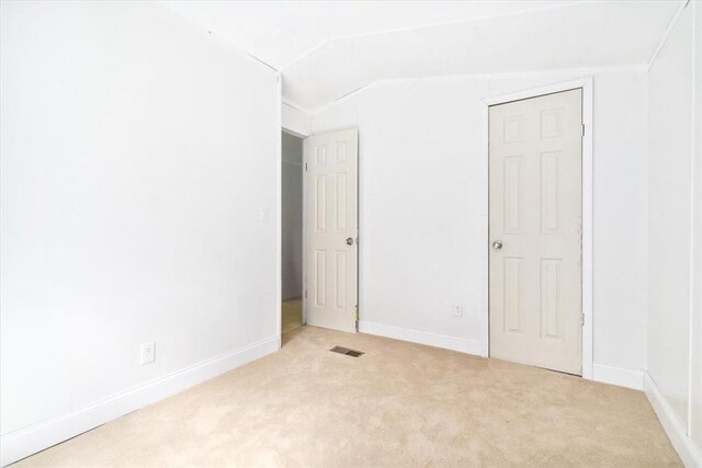 unfurnished room featuring light colored carpet and vaulted ceiling