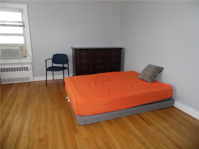 bedroom featuring radiator, light hardwood / wood-style flooring, and cooling unit