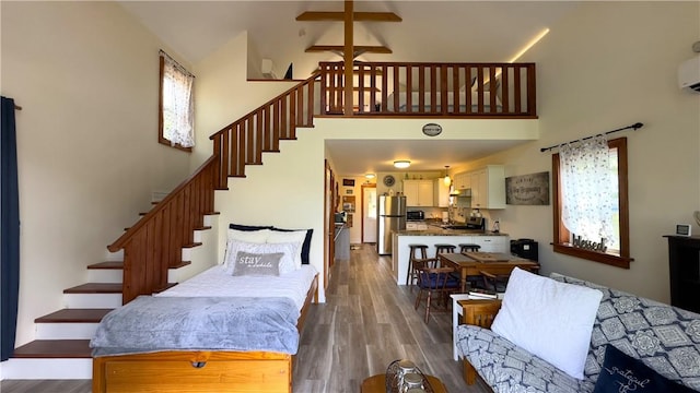 interior space featuring hardwood / wood-style flooring, high vaulted ceiling, and a wall mounted AC