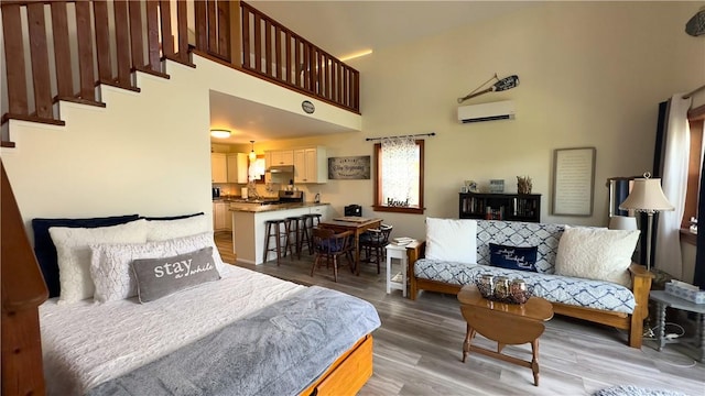 bedroom with a high ceiling, an AC wall unit, and wood-type flooring