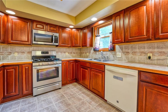 kitchen with tile countertops, decorative backsplash, stainless steel appliances, and sink