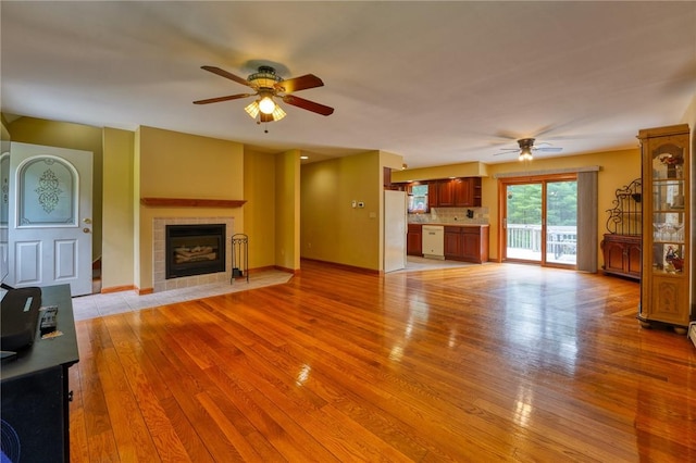 unfurnished living room with ceiling fan, a fireplace, and light hardwood / wood-style floors