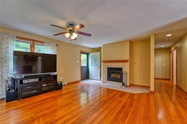 unfurnished living room with plenty of natural light, light hardwood / wood-style floors, ceiling fan, and a tiled fireplace