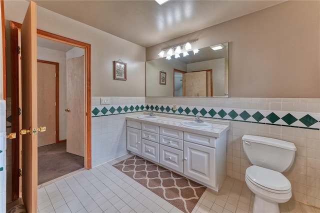 bathroom with tile patterned flooring, vanity, toilet, and tile walls