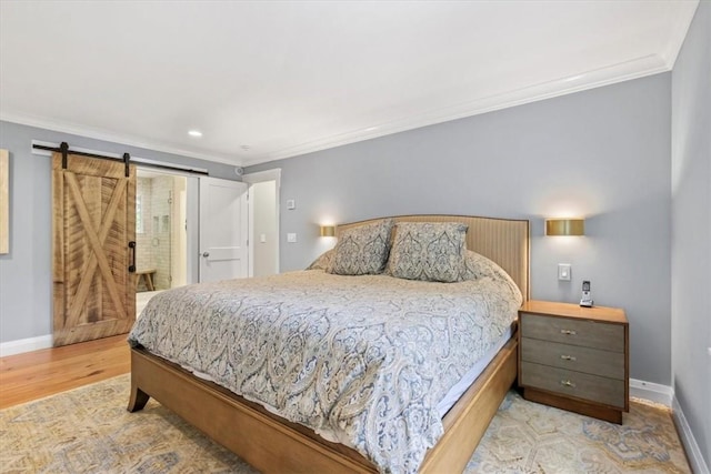 bedroom with a barn door, light hardwood / wood-style floors, and crown molding