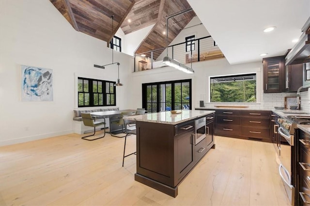 kitchen with stainless steel appliances, wooden ceiling, high vaulted ceiling, light hardwood / wood-style floors, and a kitchen island