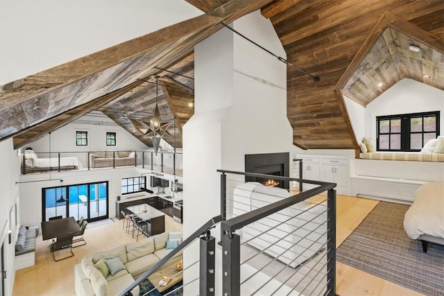 additional living space featuring beamed ceiling, light wood-type flooring, high vaulted ceiling, and a wealth of natural light