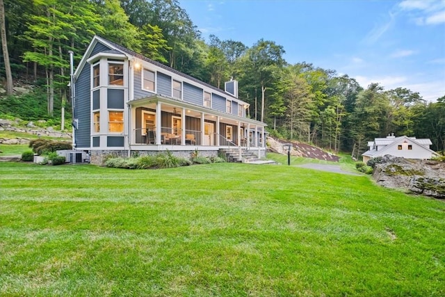 rear view of house featuring a porch, central AC unit, and a lawn