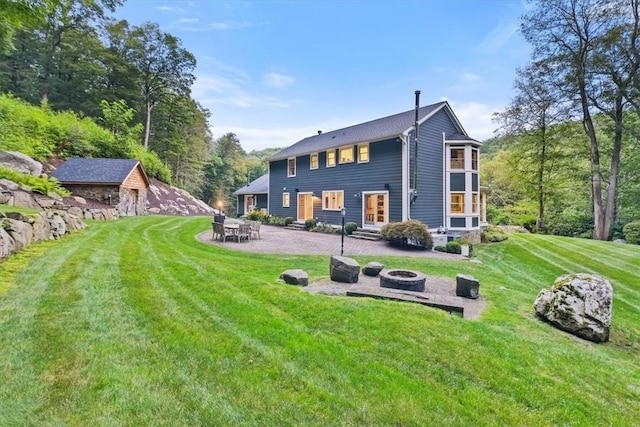 back of house with a fire pit, a patio area, and a lawn