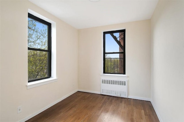 unfurnished room with radiator heating unit, dark hardwood / wood-style flooring, and plenty of natural light