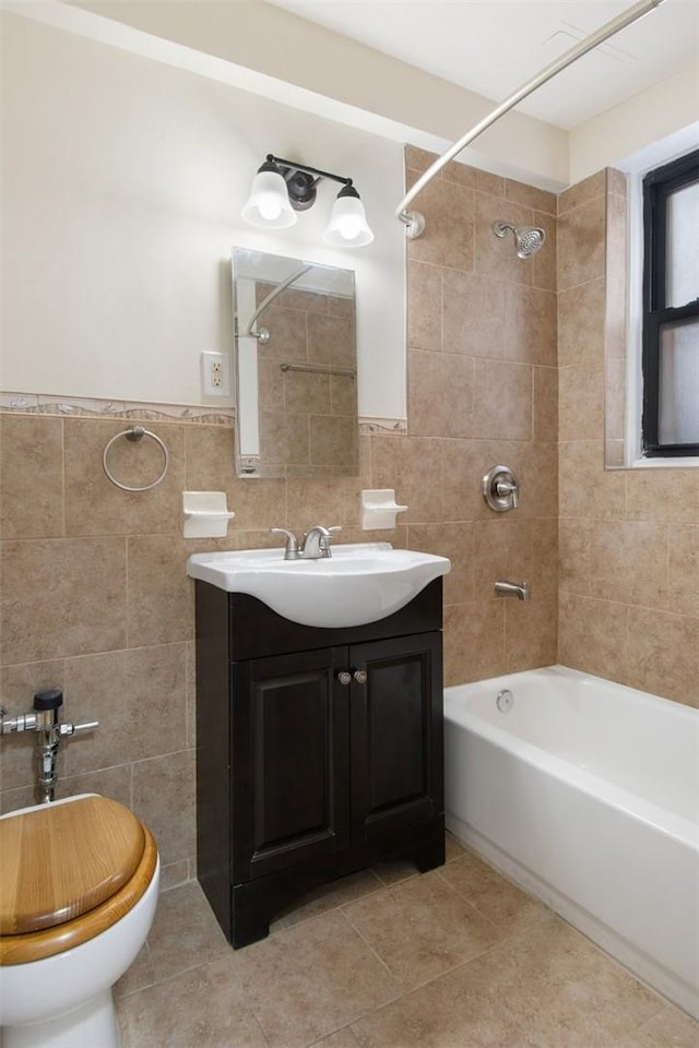 full bathroom featuring vanity, tiled shower / bath, tile patterned flooring, toilet, and tile walls