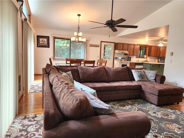 living room featuring lofted ceiling, light wood-type flooring, and ceiling fan with notable chandelier