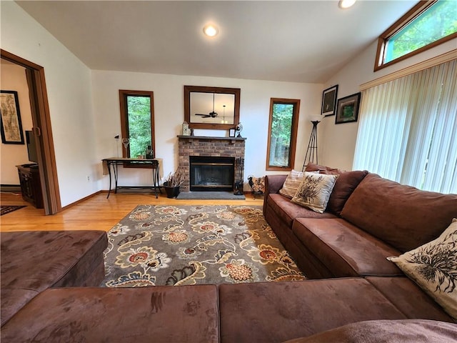 living room with hardwood / wood-style floors, vaulted ceiling, and a brick fireplace