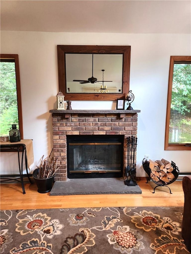 interior details featuring hardwood / wood-style flooring, ceiling fan, and a brick fireplace