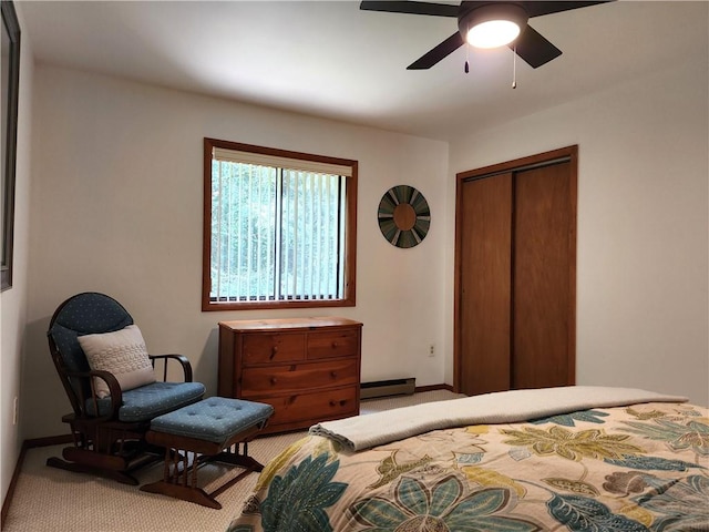 carpeted bedroom with a closet, baseboard heating, and ceiling fan