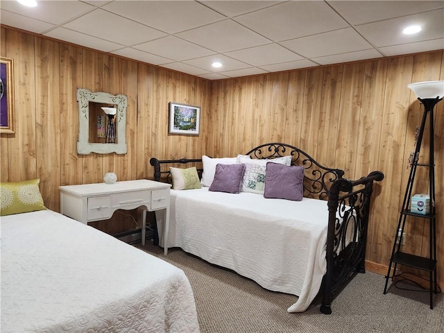 carpeted bedroom with a drop ceiling and wood walls