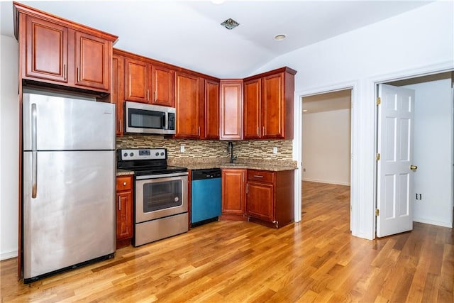 kitchen with tasteful backsplash, light hardwood / wood-style floors, vaulted ceiling, and appliances with stainless steel finishes