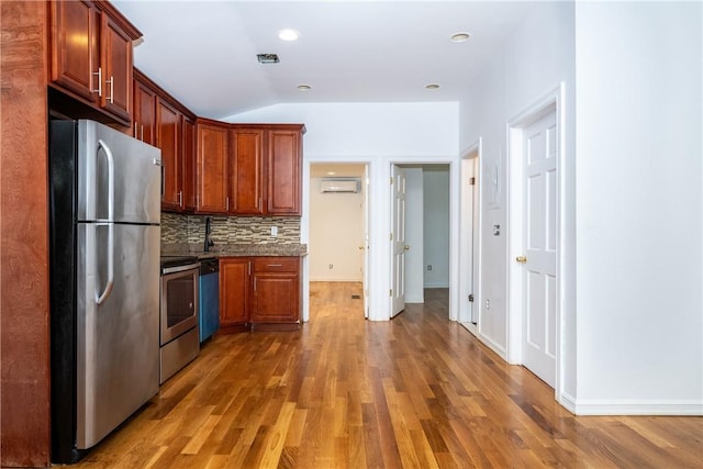 kitchen featuring dark hardwood / wood-style flooring, tasteful backsplash, stainless steel appliances, vaulted ceiling, and an AC wall unit