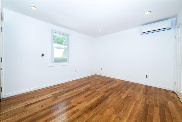 empty room with a wall mounted air conditioner and wood-type flooring