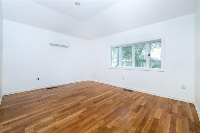 empty room featuring hardwood / wood-style flooring and a wall mounted AC