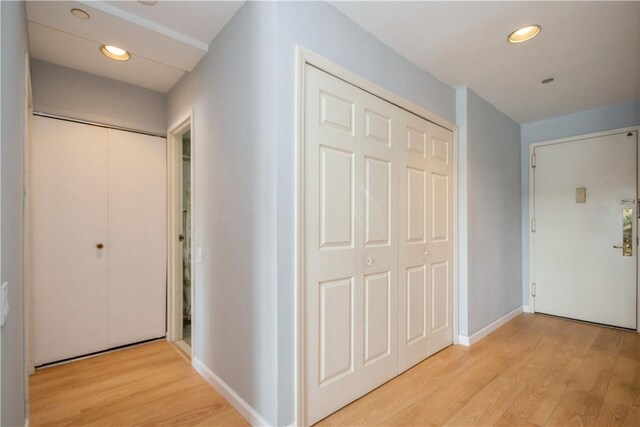 hallway featuring light wood-style floors, baseboards, and recessed lighting