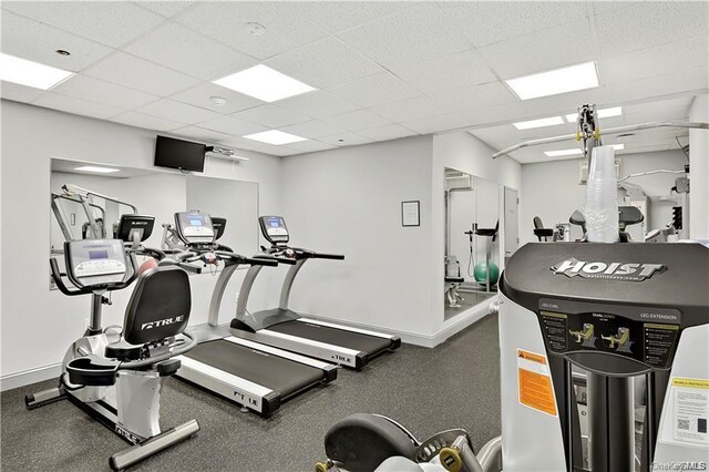 exercise room with a paneled ceiling and baseboards