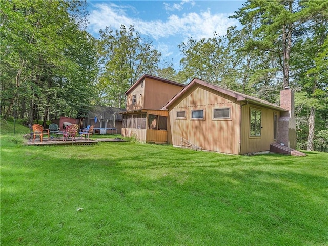 back of house with a sunroom, a yard, and a trampoline