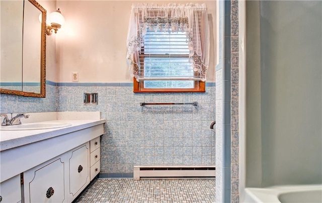 bathroom with tile patterned floors, vanity, baseboard heating, and tile walls