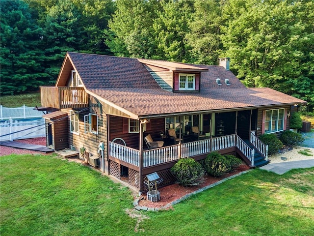 back of property with a lawn and a pool