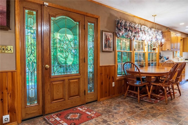 foyer entrance featuring wooden walls and an inviting chandelier