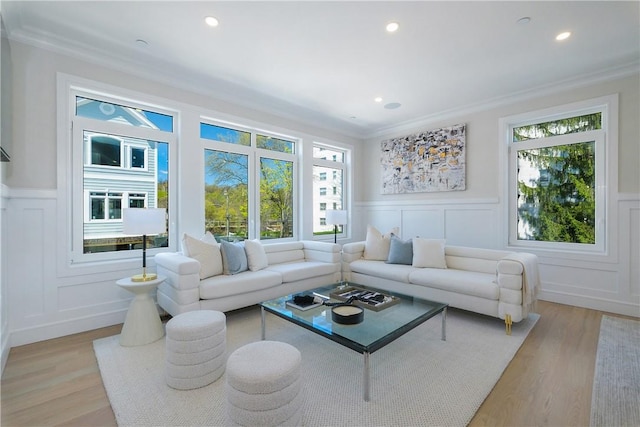 living room with light wood-type flooring, a wealth of natural light, and ornamental molding