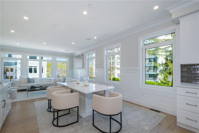 dining area with plenty of natural light, light hardwood / wood-style floors, and ornamental molding