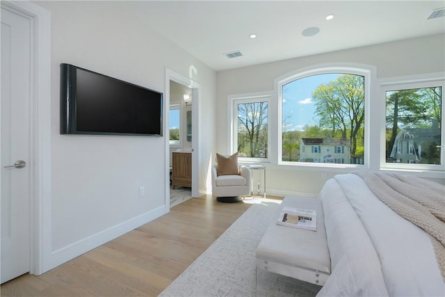 bedroom with ensuite bathroom and light hardwood / wood-style floors