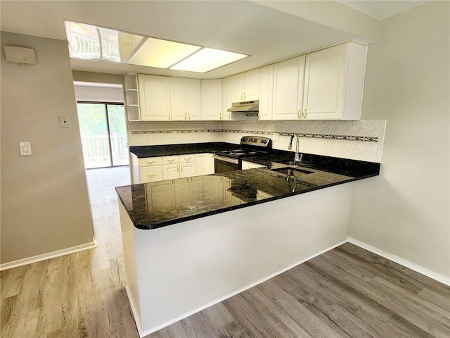 kitchen with kitchen peninsula, sink, white cabinets, and stainless steel range with electric stovetop