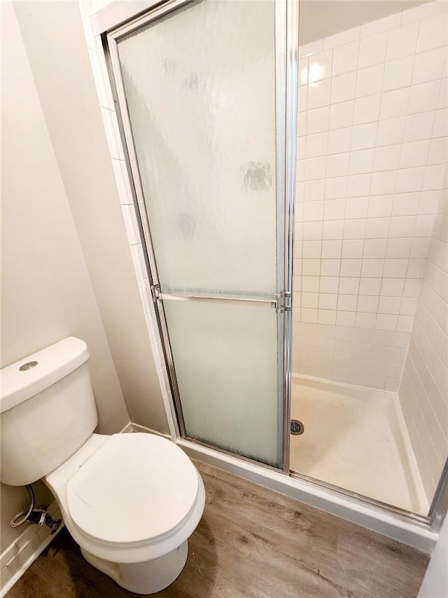 bathroom featuring hardwood / wood-style flooring, toilet, and walk in shower