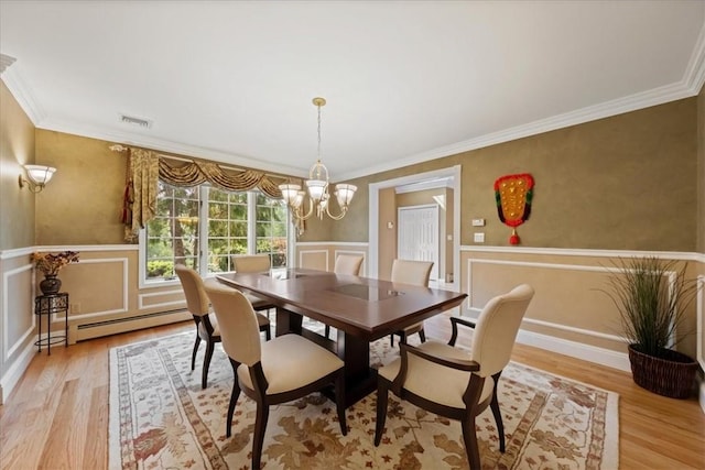 dining room featuring light wood-type flooring, a baseboard radiator, ornamental molding, and a notable chandelier