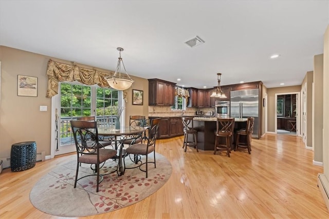 dining space with light wood-type flooring and baseboard heating