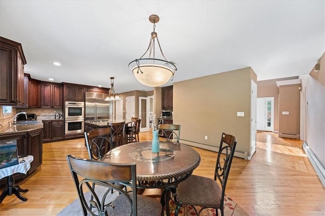 dining room with light hardwood / wood-style flooring, a baseboard radiator, and sink