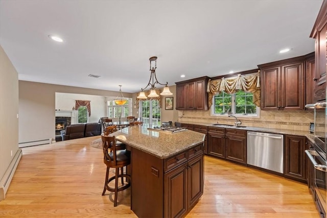 kitchen featuring a wealth of natural light, a kitchen island, stainless steel appliances, and light hardwood / wood-style floors